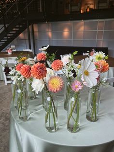 several vases filled with flowers sitting on top of a white table cloth covered table