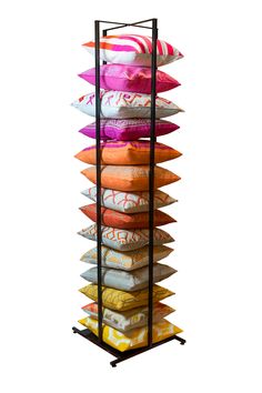 a tall rack with many pillows stacked on top of each other in front of a white background