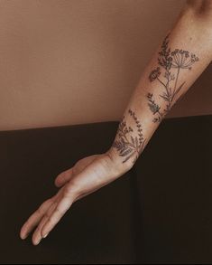 a person's arm with flowers on it and a hand reaching out to the side