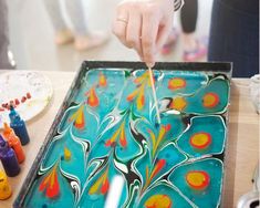 a person painting on a tray with colorful paint