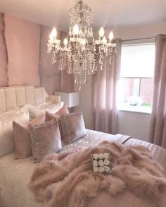 a chandelier hangs from the ceiling above a bed in a bedroom with pink walls