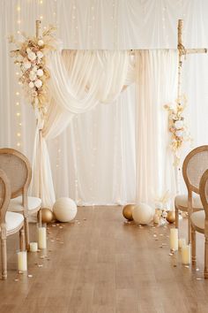 a wedding ceremony setup with white drapes and gold candles in front of the altar