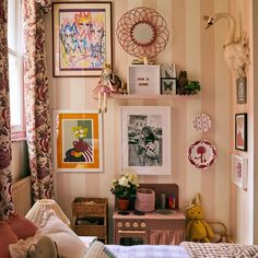 a bedroom with pink and white striped walls, pictures on the wall and toys in baskets