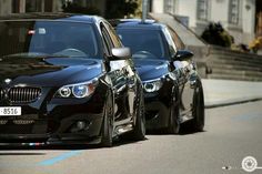 two black cars are parked on the street