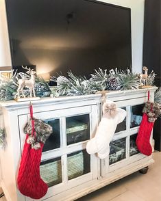 christmas stockings hanging from the side of a white entertainment center