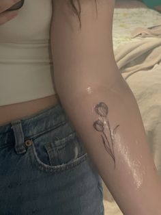 a woman's arm with a flower tattoo on the left side of her arm