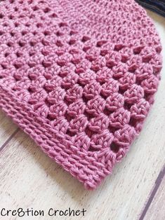 a pink crocheted hat sitting on top of a wooden floor