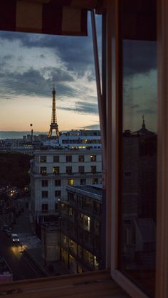 the eiffel tower is lit up at night from an apartment window in paris