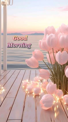 pink tulips on wooden deck with good morning message in the background and lights