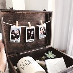 an open trunk with pictures hanging on clothes pins and photos attached to the string, next to a potted succulent plant