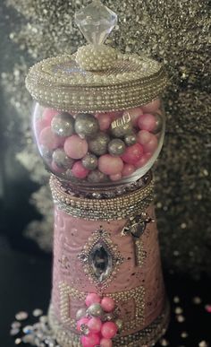 a pink and silver candy dispenser filled with lots of candies on top of a table