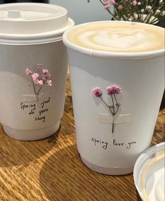 two cups with flowers painted on them sitting on a table