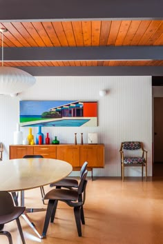 a dining room table with chairs and a painting on the wall