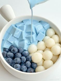 blueberries and marshmallows are being poured into a bowl