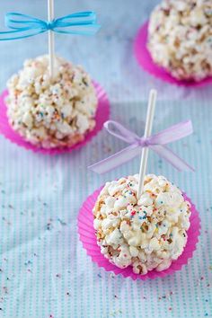 three cupcakes with sprinkles are on a blue and pink tablecloth