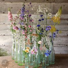 there are many vases with flowers in them on the wooden table and one is empty