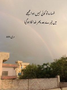 a rainbow is in the sky over a building and trees with arabic writing on it