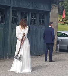 a woman in a white dress is holding a hammer and standing next to a man in a suit