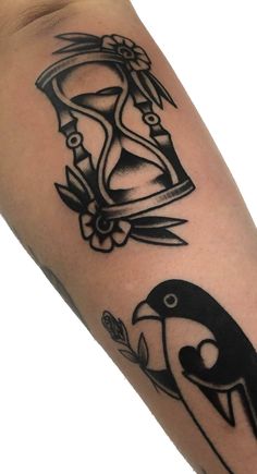 a black and white photo of a penguin with an hourglass tattoo on it's arm