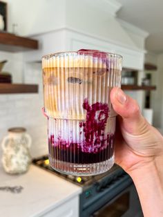 a person holding up a cupcake in the kitchen with blueberries and other toppings