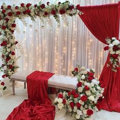 a red and white wedding ceremony setup with flowers on the bed, draped drapes and lights in the background