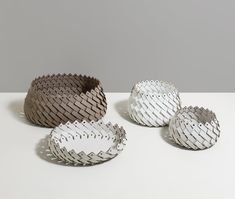 three bowls sitting on top of a white table next to each other with holes in them