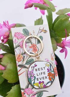 a keychain with the words best life ever on it sitting next to a potted plant