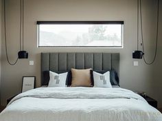 a bed with white sheets and pillows in a bedroom next to two lamps on the wall