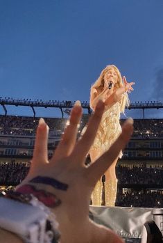 a person holding their hand up in front of a stage with a woman on it