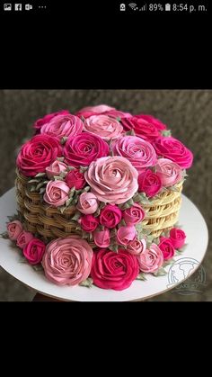 a cake decorated with pink roses on top of a white plate and wicker basket