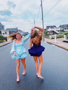 two young women are walking down the street in dresses and high heels, one is holding her hair back