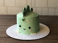 a green cake sitting on top of a wooden table next to a white polka dot plate