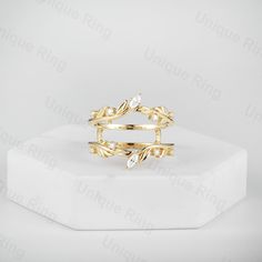 a gold ring with leaves on it sitting on top of a white surface and in front of