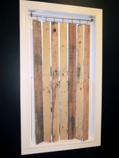 a window with wooden slats on the side and bars in the bottom half, behind which is a black wall