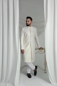 This White Long Sherwani is a stunning choice for your special occasion. Made from printed off-white khaadi silk, it features a silk kurta and cotton pajama for a comfortable fit. Complete your look with the elegant organza Rajastjhani kula (turban) and exude an air of style and sophistication. Elegant Raw Silk Sherwani Straight Kurta, Elegant Sherwani In Raw Silk With Straight Kurta, Elegant Designer Wear Sherwani With Straight Kurta, Elegant Raw Silk Sherwani With Dabka Detailing, Silk Straight Kurta Sherwani For Wedding, Silk Sherwani With Straight Kurta For Wedding, Elegant Unstitched Sherwani With Straight Kurta, Unstitched Elegant Straight Kurta Sherwani, Designer Cream Fitted Kurta