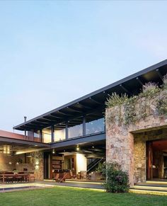 a house that has grass in front of it and some plants on the outside wall