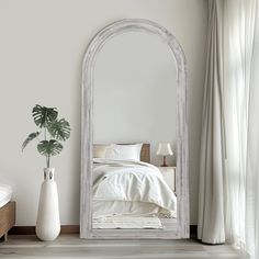 a white bed sitting next to a large mirror