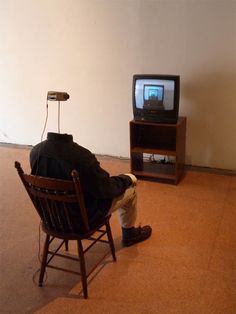 a man is sitting in a chair watching tv on the television set with his head down