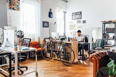 a man sitting at a desk in an office with lots of bikes on the wall