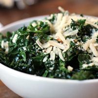 a white bowl filled with greens and cheese