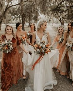 a group of women standing next to each other holding bouquets in their hands and smiling