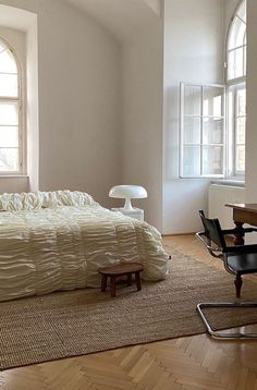 an empty bedroom with a bed, desk and chair in the corner near two windows