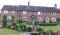 a large brick house with lots of plants in the front yard