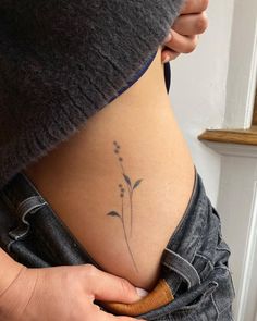 a woman's stomach with a small flower tattoo on her lower back and side