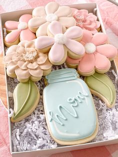 decorated cookies in a box with flowers and a mason jar on the tablecloths