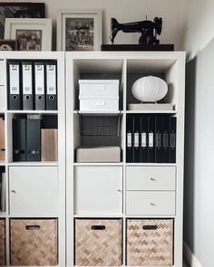 a white bookcase filled with lots of books next to a wall mounted sewing machine