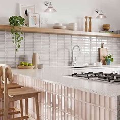 a kitchen counter with two stools in front of it and shelves above the stove