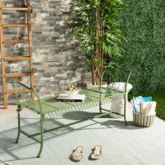 a green table sitting on top of a rug next to a brick wall and potted plant