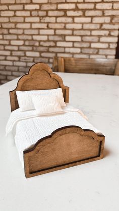 a bed made out of wood sitting on top of a white table next to a brick wall