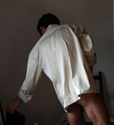 a man in white shirt and shorts standing on bed